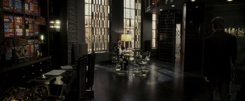 Movie still from “Lucky Number Slevin” (2006), directed by Paul McGuigan – A man sitting at a table in front of a large window; Wide shot, High angle