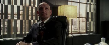 Movie still from “Lucky Number Slevin” (2006), directed by Paul McGuigan – A man in a suit and tie sitting in a chair; Close Up shot, Over the shoulder angle