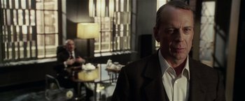 Movie still from “Lucky Number Slevin” (2006), directed by Paul McGuigan – A man in a suit standing in front of a table; Close Up shot, Over the shoulder angle