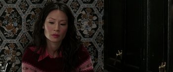 Movie still from “Lucky Number Slevin” (2006), directed by Paul McGuigan – A woman sitting in front of an ornate wall; Close Up shot, High angle