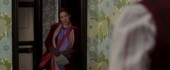 Movie still from “Lucky Number Slevin” (2006), directed by Paul McGuigan – A woman standing in front of a wall holding a purse; Medium shot, Over the shoulder angle