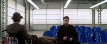 Movie still from “Lucky Number Slevin” (2006), directed by Paul McGuigan – A man sitting on a chair in an airport; Wide shot, Low angle