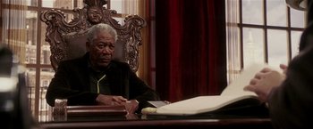 Movie still from “Lucky Number Slevin” (2006), directed by Paul McGuigan – An older man sitting at a table in front of papers; Medium shot, Low angle