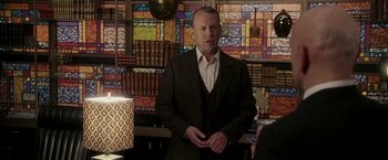 Movie still from “Lucky Number Slevin” (2006), directed by Paul McGuigan – A man in a suit and tie in front of a stained glass window; Medium shot, Over the shoulder angle