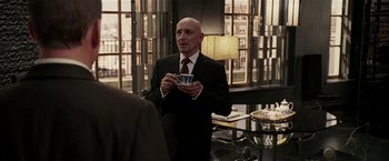 Movie still from “Lucky Number Slevin” (2006), directed by Paul McGuigan – A man in a suit and tie holding a coffee cup; Medium shot, Over the shoulder angle