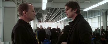 Movie still from “Lucky Number Slevin” (2006), directed by Paul McGuigan – Two men in suits talking to each other in a crowded area; Close Up shot, Over the shoulder angle