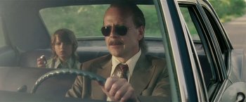 Movie still from “Lucky Number Slevin” (2006), directed by Paul McGuigan – A man in a suit and sunglasses driving a car; Close Up shot, Low angle