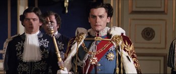 Movie still from “Ludwig” (1973), directed by Luchino Visconti – A man dressed in a royal outfit holding a scepter; Medium shot, Low angle