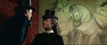 Movie still from “Ludwig” (1973), directed by Luchino Visconti – A woman wearing a top hat and a black dress; Medium shot, Over the shoulder angle