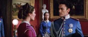 Movie still from “Ludwig” (1973), directed by Luchino Visconti – A man and a woman standing next to each other in a room; Medium shot, Low angle