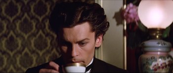 Movie still from “Ludwig” (1973), directed by Luchino Visconti – A person drinking a cup of coffee; Close Up shot, High angle