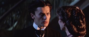 Movie still from “Ludwig” (1973), directed by Luchino Visconti – A man in a black suit and a woman in a black dress; Close Up shot, Over the shoulder angle