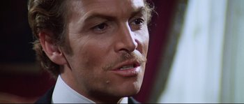 Movie still from “Ludwig” (1973), directed by Luchino Visconti – A man with a mustache looking at the camera; Close Up shot, Over the shoulder angle