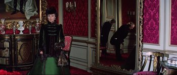 Movie still from “Ludwig” (1973), directed by Luchino Visconti – A woman standing in front of a mirror in a room; Wide shot, Over the shoulder angle