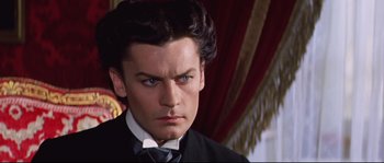 Movie still from “Ludwig” (1973), directed by Luchino Visconti – A person wearing a suit and tie; Close Up shot, Over the shoulder angle