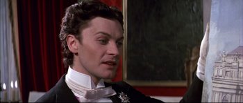 Movie still from “Ludwig” (1973), directed by Luchino Visconti – A person wearing a suit and tie; Close Up shot, Over the shoulder angle