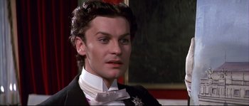 Movie still from “Ludwig” (1973), directed by Luchino Visconti – A person wearing a suit and bow tie; Close Up shot, High angle