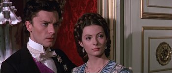 Movie still from “Ludwig” (1973), directed by Luchino Visconti – A man and a woman in formal dress looking at the camera; Close Up shot, Over the shoulder angle