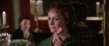 Movie still from “Ludwig” (1973), directed by Luchino Visconti – A woman holding a pink flower in her hand; Close Up shot, Over the shoulder angle