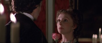 Movie still from “Ludwig” (1973), directed by Luchino Visconti – A woman holding a pink rose in front of a man; Close Up shot, Over the shoulder angle