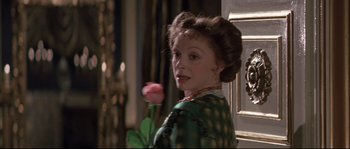 Movie still from “Ludwig” (1973), directed by Luchino Visconti – A woman in a green dress holding a pink flower; Close Up shot, Over the shoulder angle