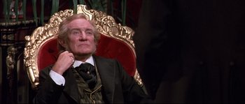 Movie still from “Ludwig” (1973), directed by Luchino Visconti – An older man sitting in a chair in front of a wall; Close Up shot, Low angle