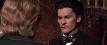 Movie still from “Ludwig” (1973), directed by Luchino Visconti – A person wearing a suit and a bow tie; Close Up shot, Over the shoulder angle