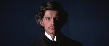 Movie still from “Ludwig” (1973), directed by Luchino Visconti – A person wearing a suit and tie; Close Up shot, Low angle