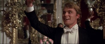 Movie still from “Ludwig” (1973), directed by Luchino Visconti – A man in a tuxedo raising his hand in the air; Close Up shot, Low angle