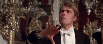 Movie still from “Ludwig” (1973), directed by Luchino Visconti – A man in a tuxedo is holding his hand up; Close Up shot, Low angle