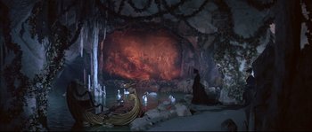 Movie still from “Ludwig” (1973), directed by Luchino Visconti – A woman in a black dress standing in front of a cave; Extreme Wide shot, High angle