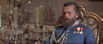 Movie still from “Ludwig” (1973), directed by Luchino Visconti – A man with a long beard wearing a blue suit; Close Up shot, Low angle