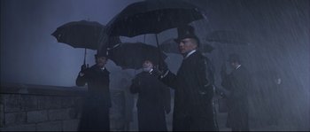 Movie still from “Ludwig” (1973), directed by Luchino Visconti – A group of men standing next to each other under an umbrella; Medium shot, Low angle