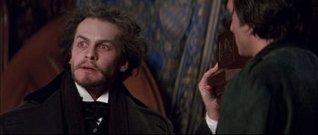 Movie still from “Ludwig” (1973), directed by Luchino Visconti – A man with a beard is holding a chocolate bar; Close Up shot, Low angle