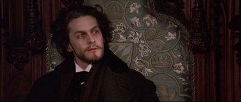 Movie still from “Ludwig” (1973), directed by Luchino Visconti – A person wearing a suit and tie; Close Up shot, High angle