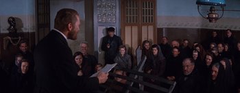 Movie still from “Lust for Life” (1956), directed by George Cukor – A group of people sitting in front of a building; Wide shot, High angle