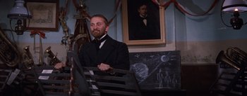 Movie still from “Lust for Life” (1956), directed by George Cukor – A man sitting on a bench in front of a chalkboard; Medium shot, Low angle