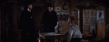 Movie still from “Lust for Life” (1956), directed by George Cukor – A man in a top hat standing in front of a table; Medium shot, Over the shoulder angle