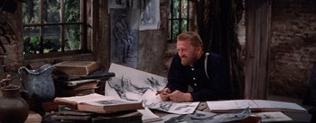 Movie still from “Lust for Life” (1956), directed by George Cukor – A man sitting at a table with some drawings; Medium shot, High angle