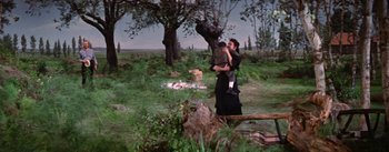 Movie still from “Lust for Life” (1956), directed by George Cukor – A woman holding a child in her arms in a wooded area; Wide shot, High angle