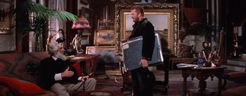 Movie still from “Lust for Life” (1956), directed by George Cukor – A man carrying a television in a living room; Medium shot, Over the shoulder angle