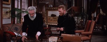 Movie still from “Lust for Life” (1956), directed by George Cukor – Two men in a room with paintings on the wall; Medium shot, Low angle