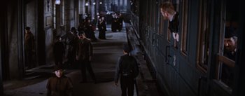 Movie still from “Lust for Life” (1956), directed by George Cukor – A group of people standing next to each other on a sidewalk; Wide shot, High angle