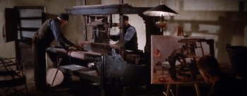 Movie still from “Lust for Life” (1956), directed by George Cukor – A man working on a machine in a room; Wide shot, High angle