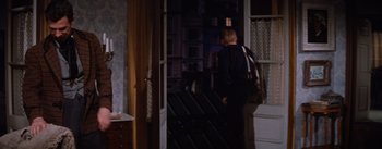 Movie still from “Lust for Life” (1956), directed by George Cukor – A man standing in a room with a backpack; Wide shot, High angle