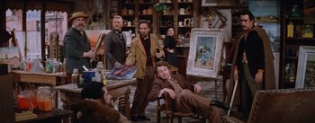 Movie still from “Lust for Life” (1956), directed by George Cukor – A group of people sitting in a room with paintings; Wide shot, High angle
