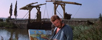 Movie still from “Lust for Life” (1956), directed by George Cukor – A man is painting a picture near a bridge; Medium shot, Low angle