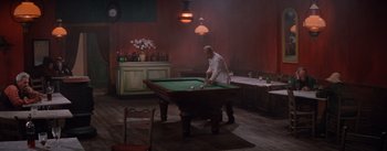 Movie still from “Lust for Life” (1956), directed by George Cukor – An old man playing pool in a dark room; Wide shot, High angle