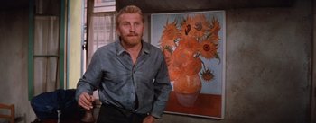 Movie still from “Lust for Life” (1956), directed by George Cukor – A man standing in front of a painting of sunflowers; Medium shot, Low angle