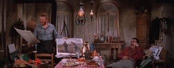 Movie still from “Lust for Life” (1956), directed by George Cukor – A person holding a picture of a man in a kitchen; Medium shot, Over the shoulder angle